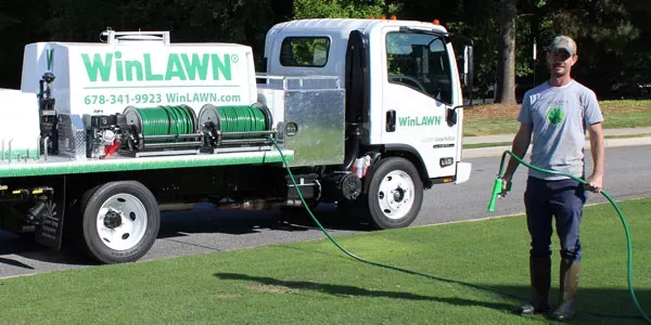 Tech standing with hose in front lawn getting ready to spray yard